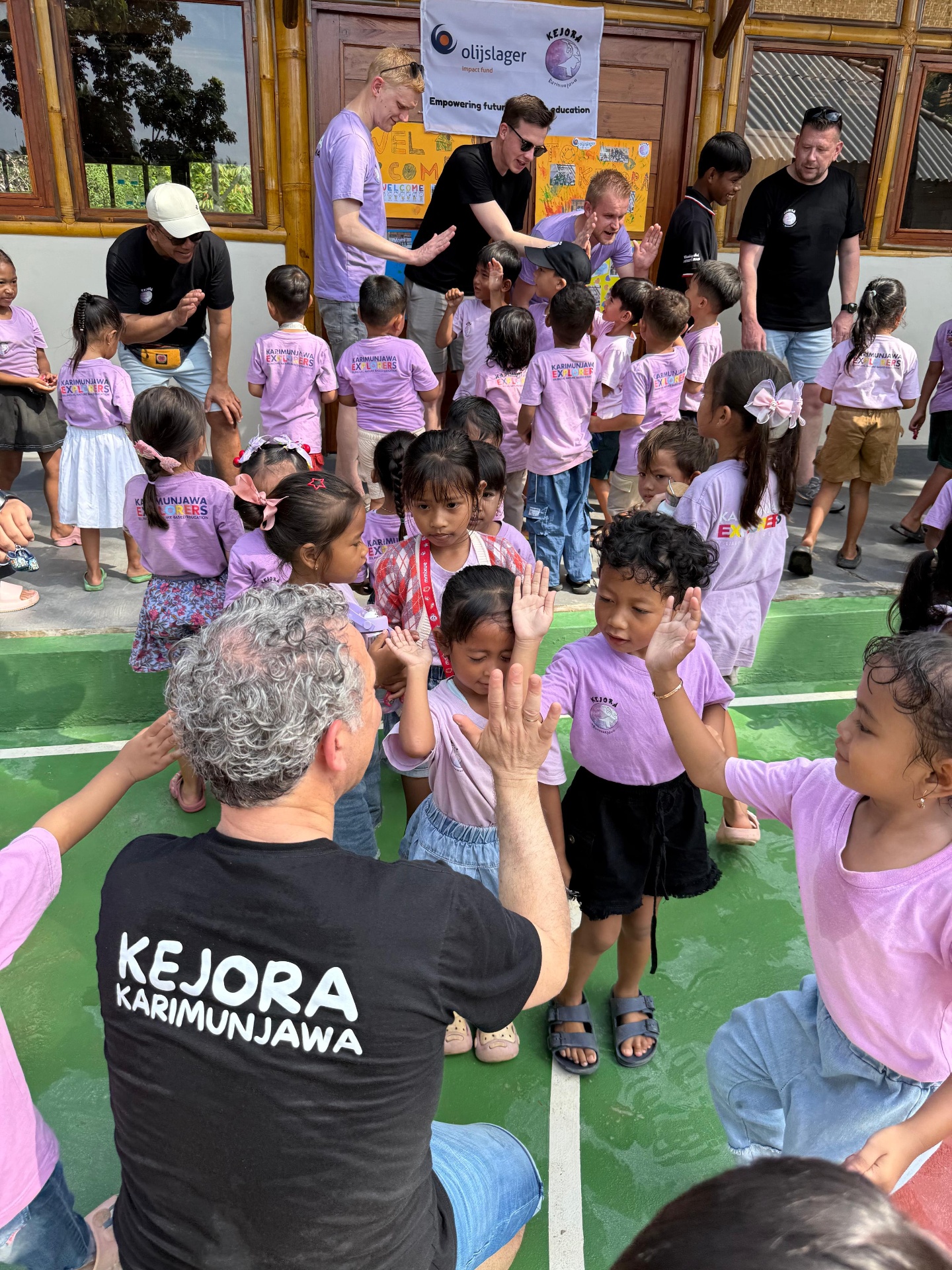 Kejora volunteers high-fiving children during an outdoor activity in Karimunjawa
